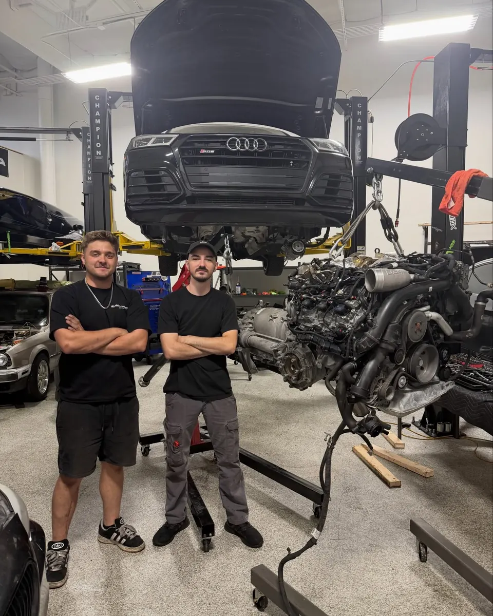 Two EuroWorks techs in front of an Audi SQ5 with its engine out on a stand