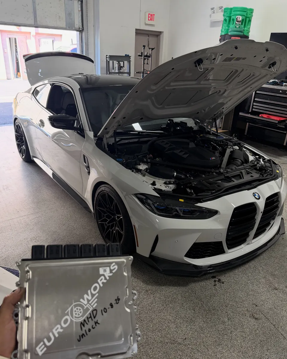 A G8X M4 in the EuroWorks shop with its ECU on the bench, labelled EuroWorks