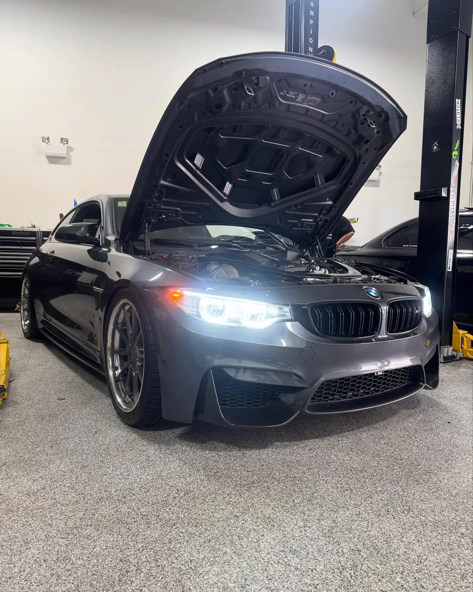 An F82 M4 on the lift with the hood open during a pre-purchase inspection