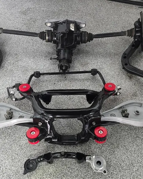 An E46 M3 rear subframe rebuilt with new red polyurethane bushings, laid out on the shop floor
